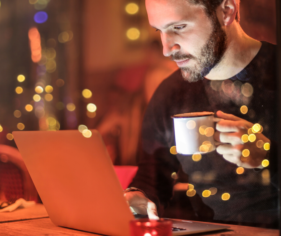 Man drinking coffee and using laptop in the evening